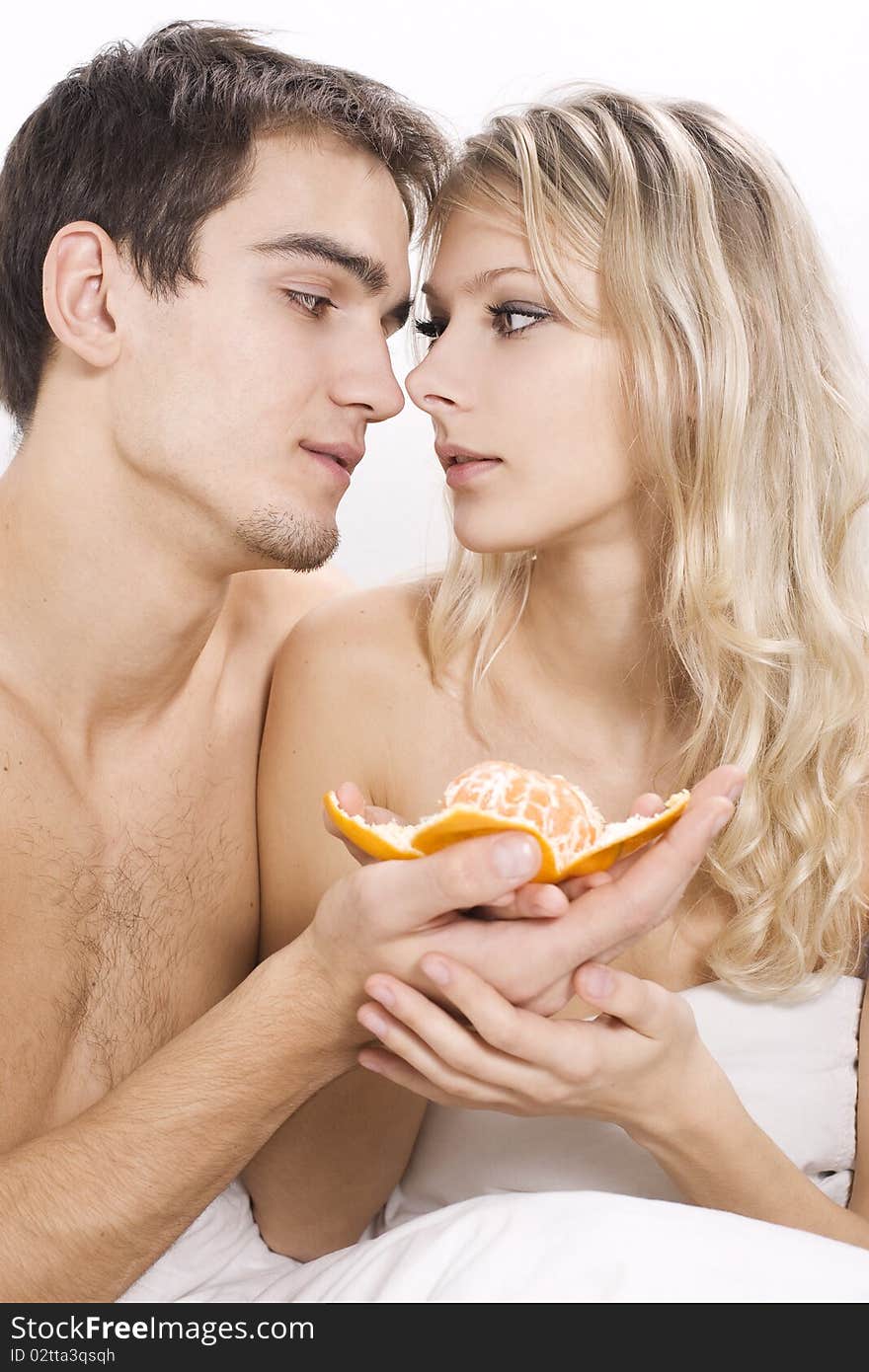 Young couple enjoying fruit breakfast in bed. Young couple enjoying fruit breakfast in bed