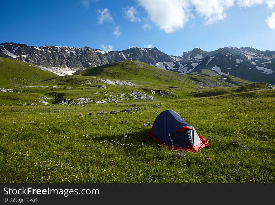 Tent on green grass in the high mountains