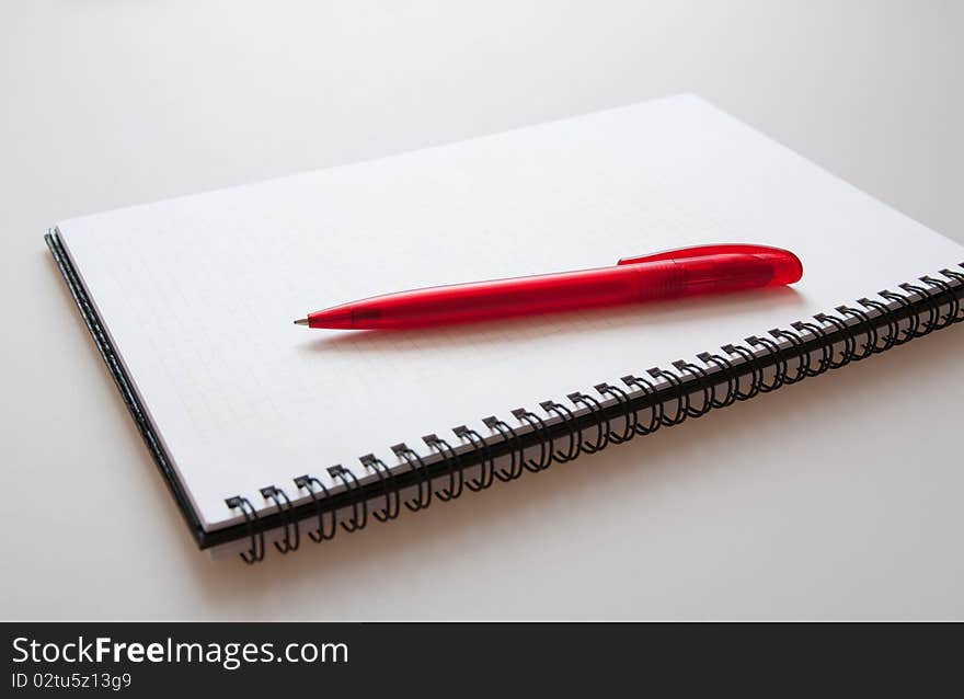 Notepad with pen on light-grey background