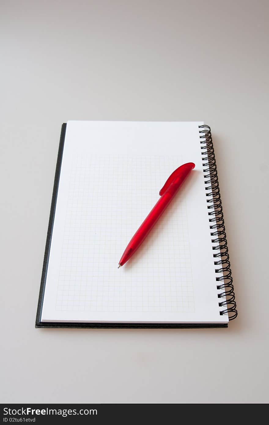 Notepad with pen on light-grey background