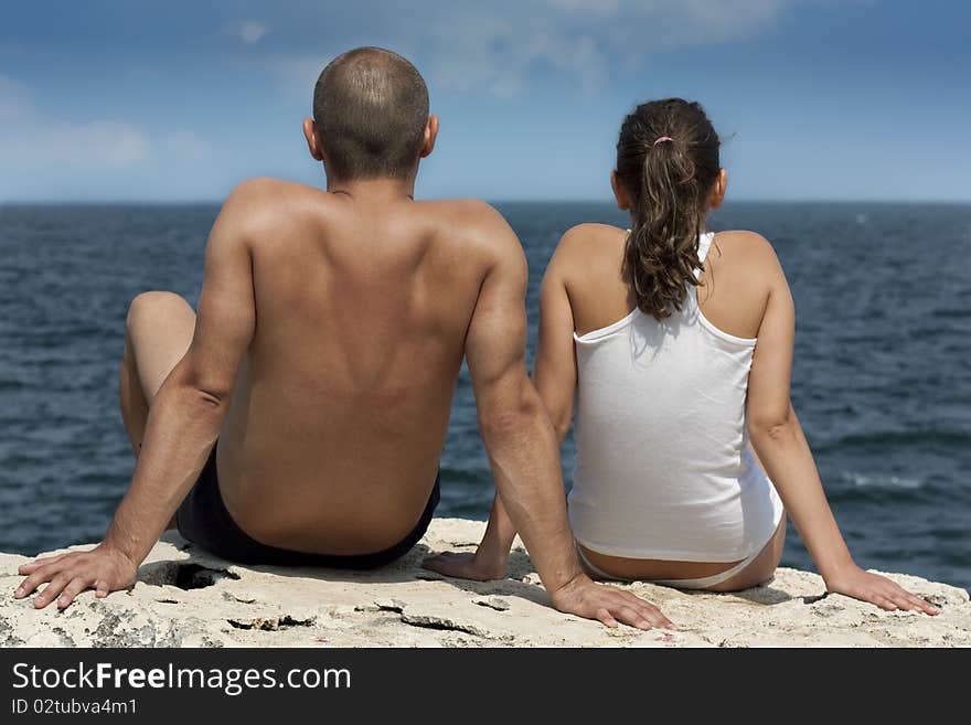 Young couple sitting on a clif
f and looking at sea. Young couple sitting on a clif
f and looking at sea