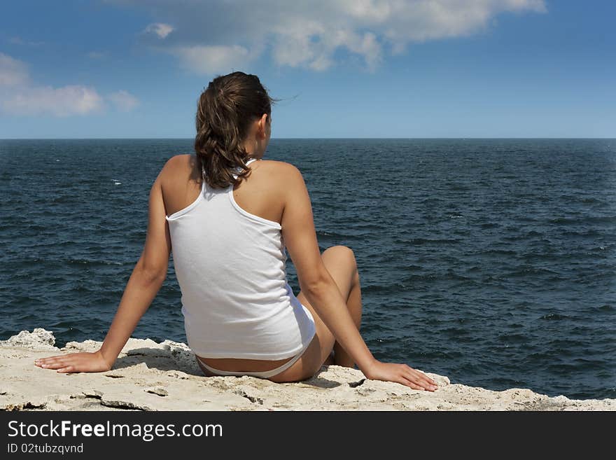 Young woman on a cliff looking at sea. Young woman on a cliff looking at sea