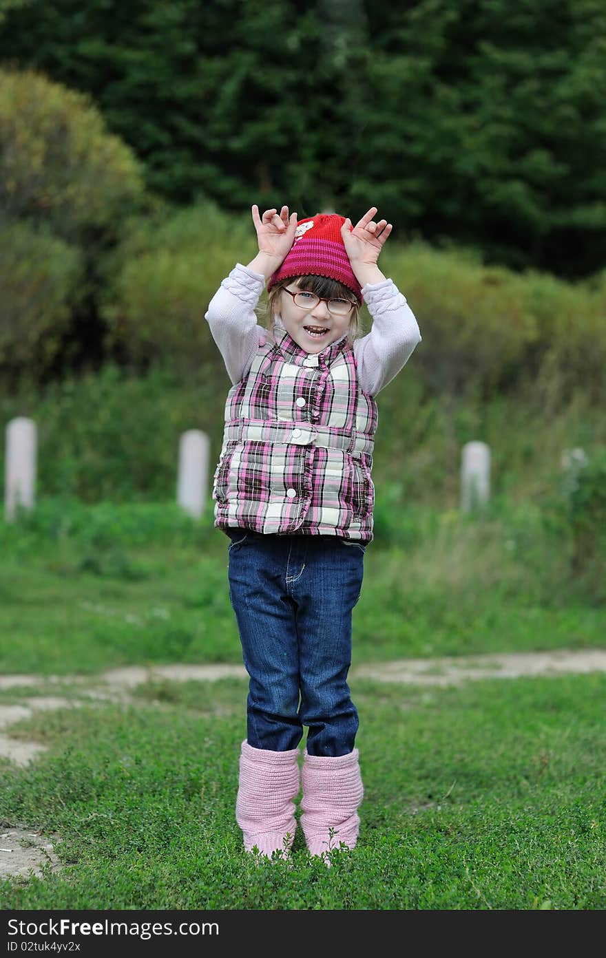 Adorable small girl in bright pink hat glasses on beauty autumn background