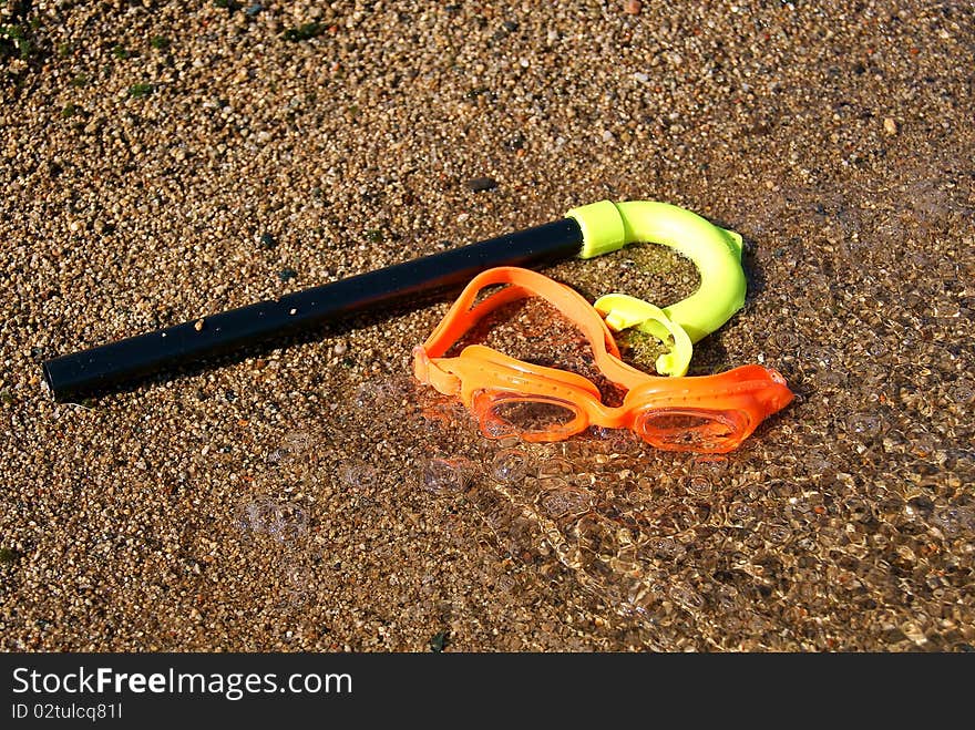 On a beach, on sand glasses and a tube for swimming lay. On a beach, on sand glasses and a tube for swimming lay