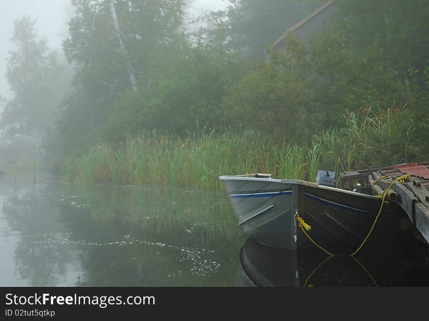 Boat tied to a dock on a misty lake. Boat tied to a dock on a misty lake