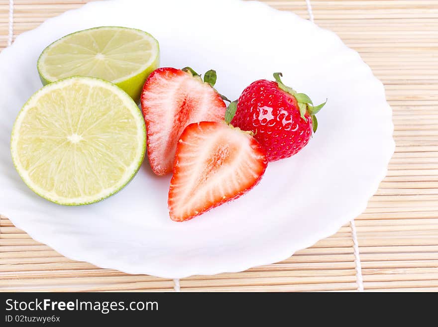 Strawberries and lime on white plate, closed-up