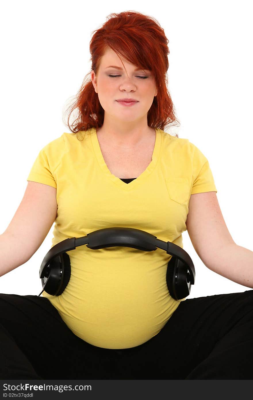 Beautiful pregnant 23 year old american woman with headphones on belly over white. Beautiful pregnant 23 year old american woman with headphones on belly over white.