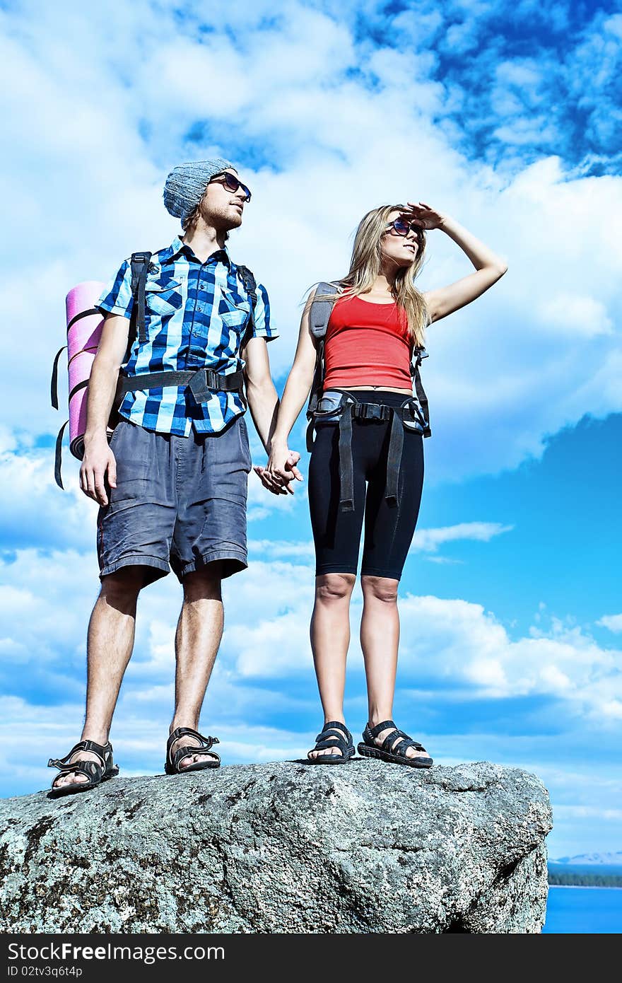 Couple of tourists are standing at the top of a mountain with a feeling of freedom. Couple of tourists are standing at the top of a mountain with a feeling of freedom.