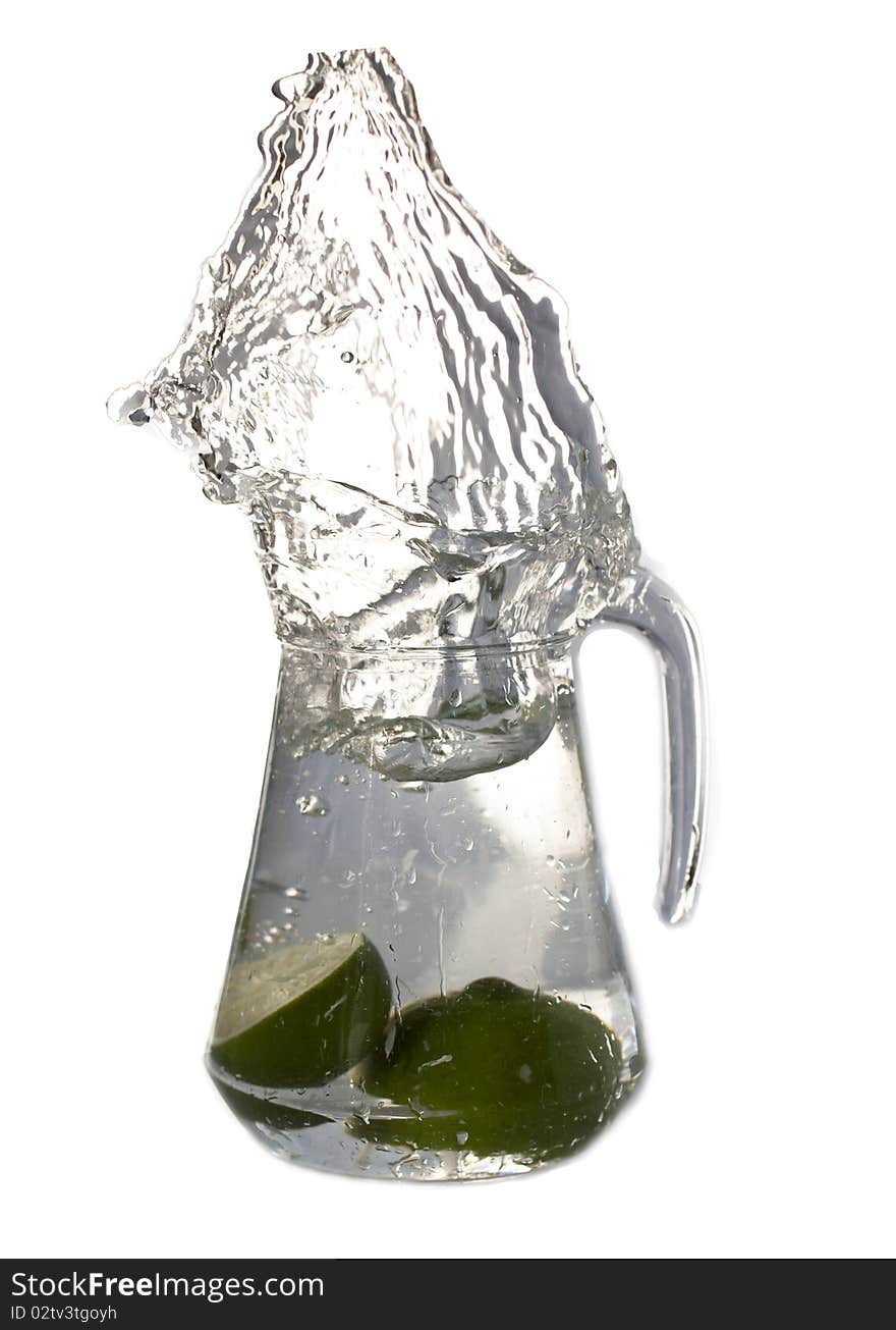 Water splashing from a carafe full with water and some limes