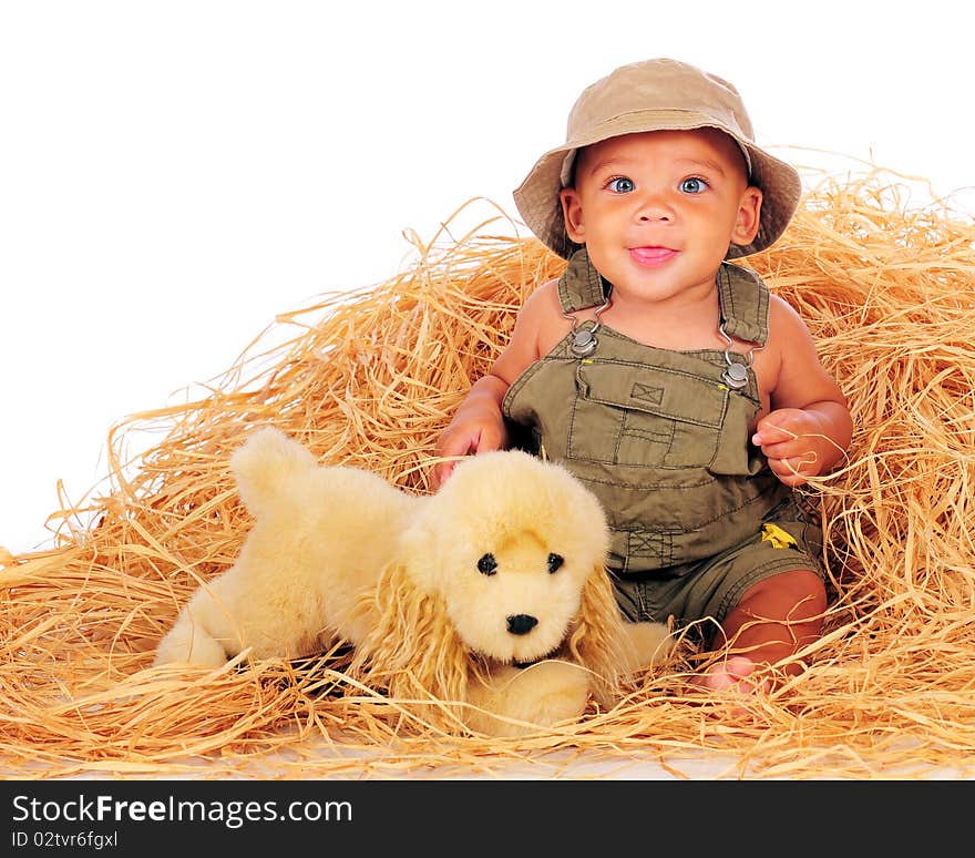 A happy, biracial baby boy in overalls playing in a pile of hay with his toy pup.  Isolated on white. A happy, biracial baby boy in overalls playing in a pile of hay with his toy pup.  Isolated on white.