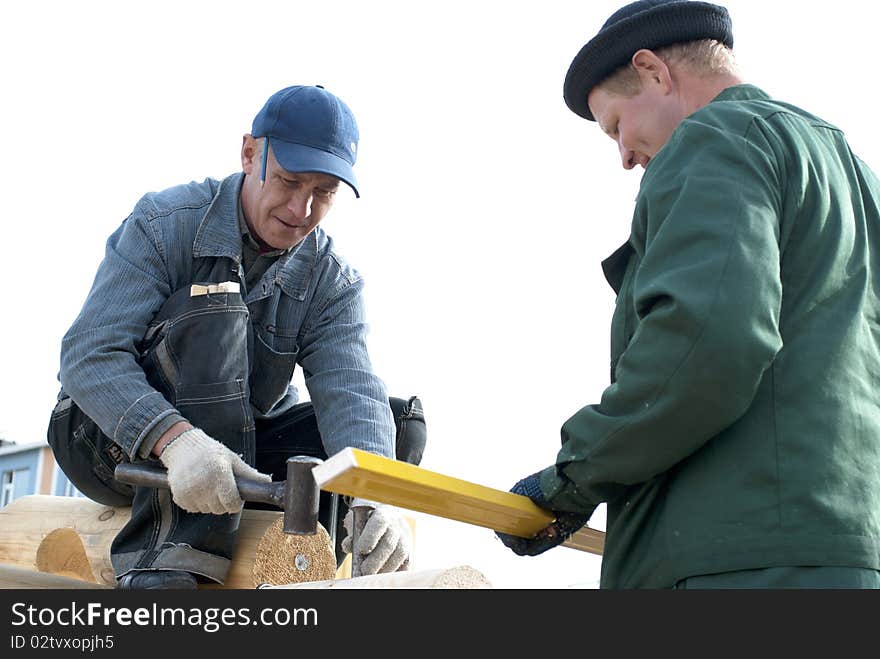 Carpenters works on the wall of log cabin. Carpenters works on the wall of log cabin