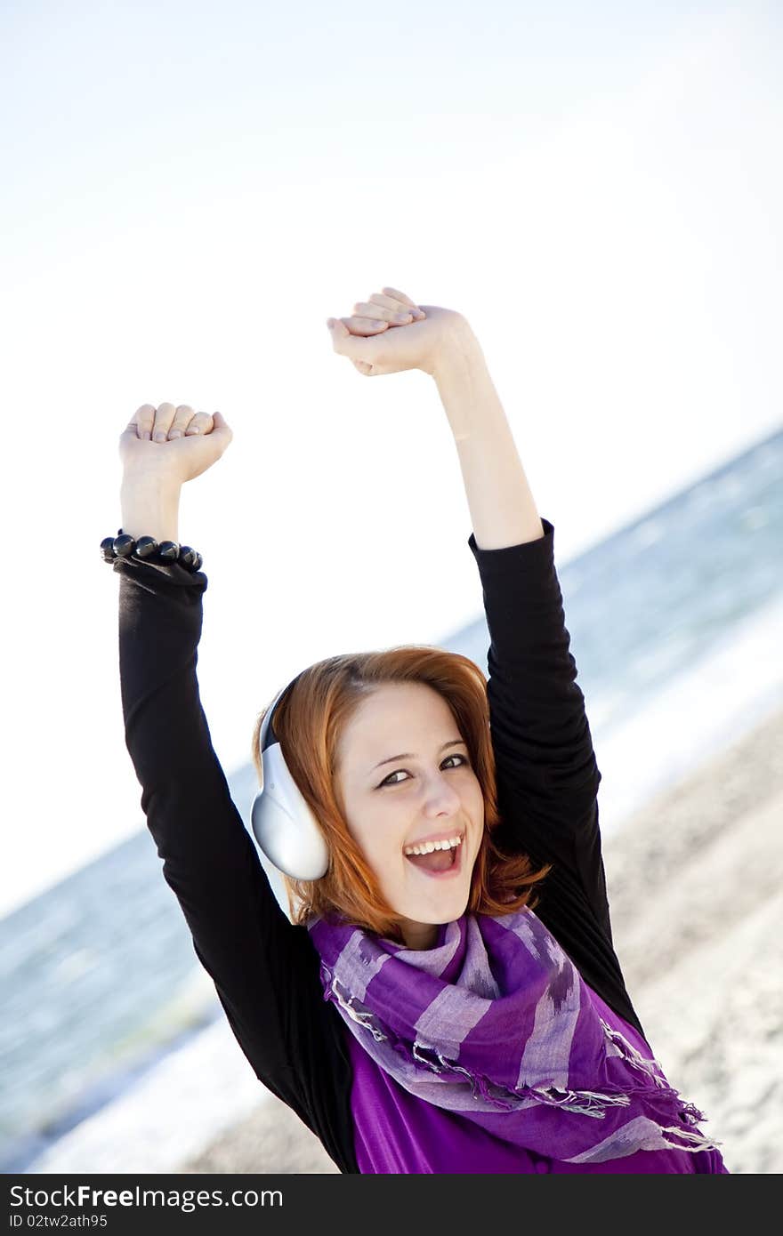 Portrait of red-haired girl in cap with headphone on the beach. Portrait of red-haired girl in cap with headphone on the beach.