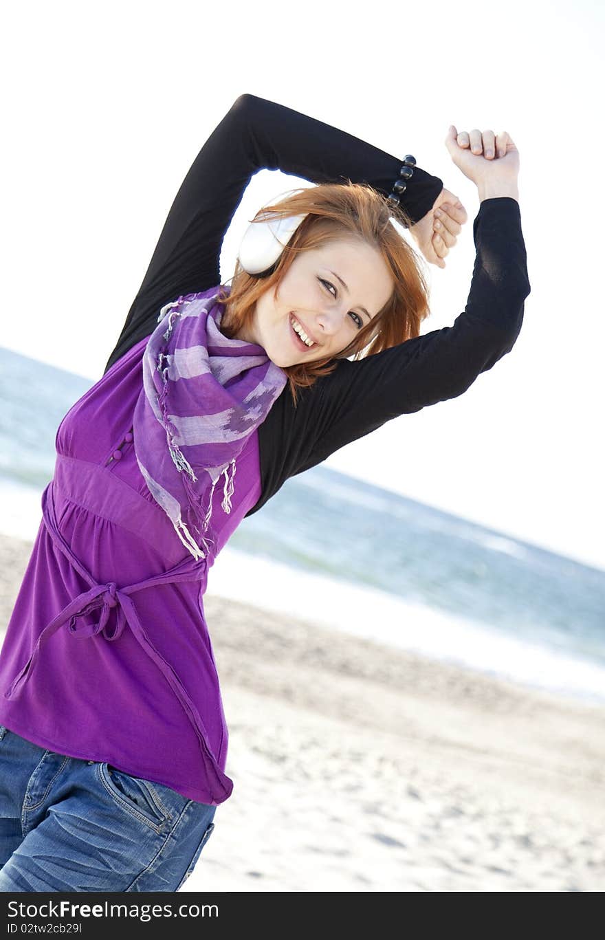 Portrait of red-haired girl in cap with headphone on the beach. Portrait of red-haired girl in cap with headphone on the beach.