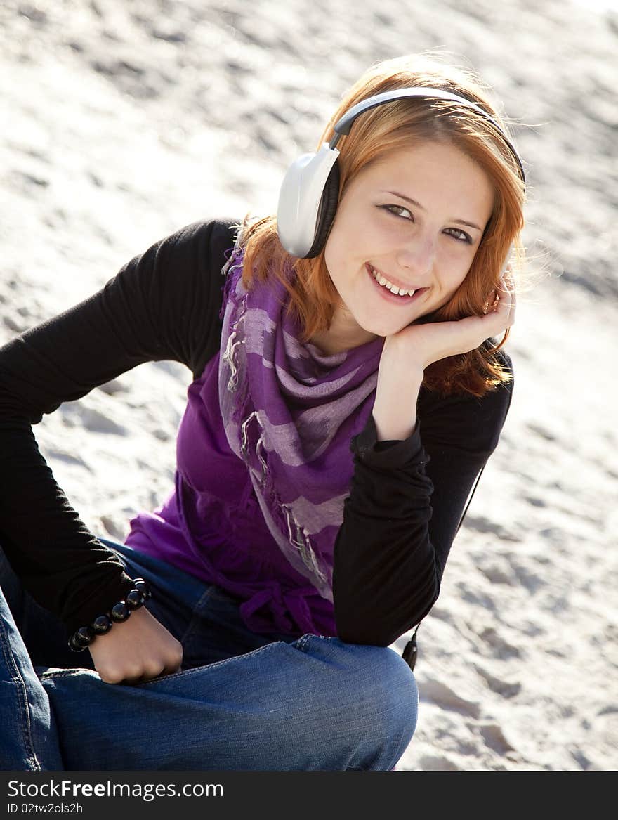 Portrait of red-haired girl in cap with headphone on the beach. Portrait of red-haired girl in cap with headphone on the beach.