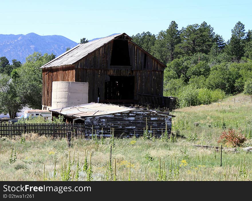 This is an old abandoned barn in a field with mountains in the background
