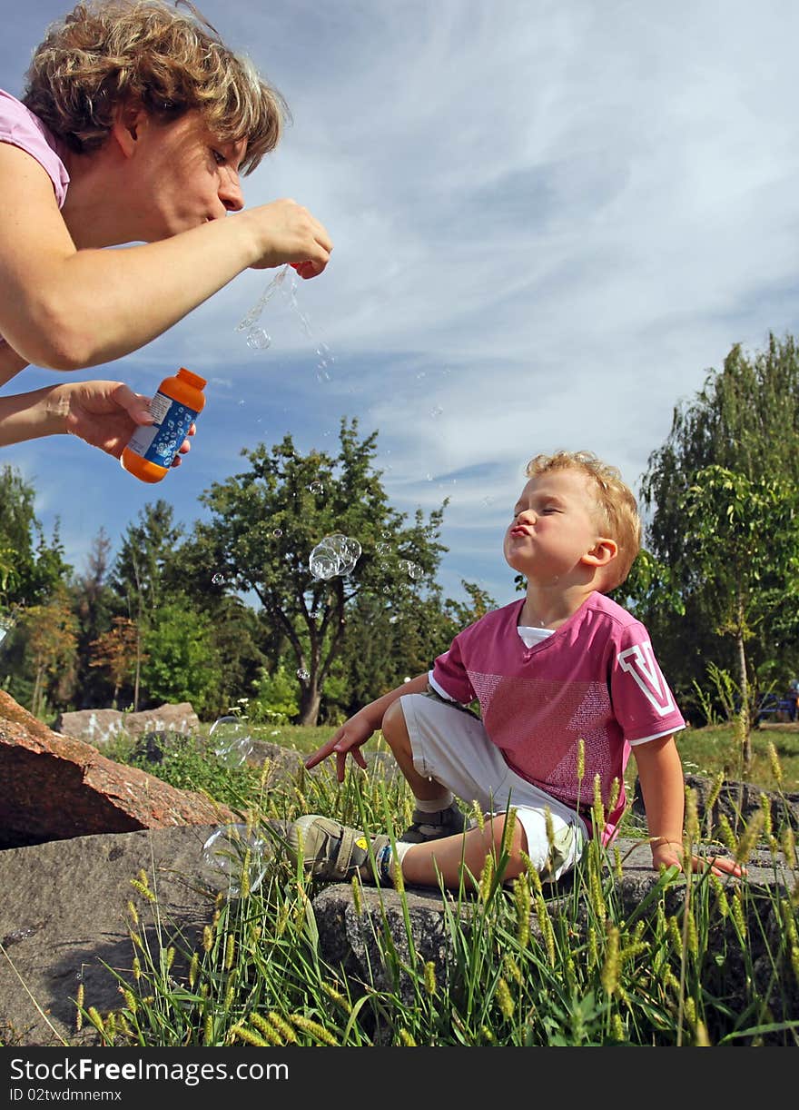 Mother and son blowing soap bubbles in a park