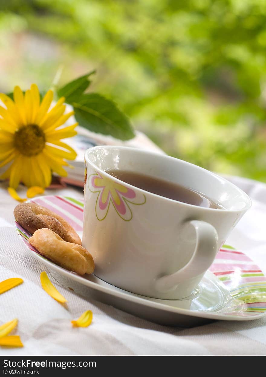 Tea with cookies, the book and flowers on background