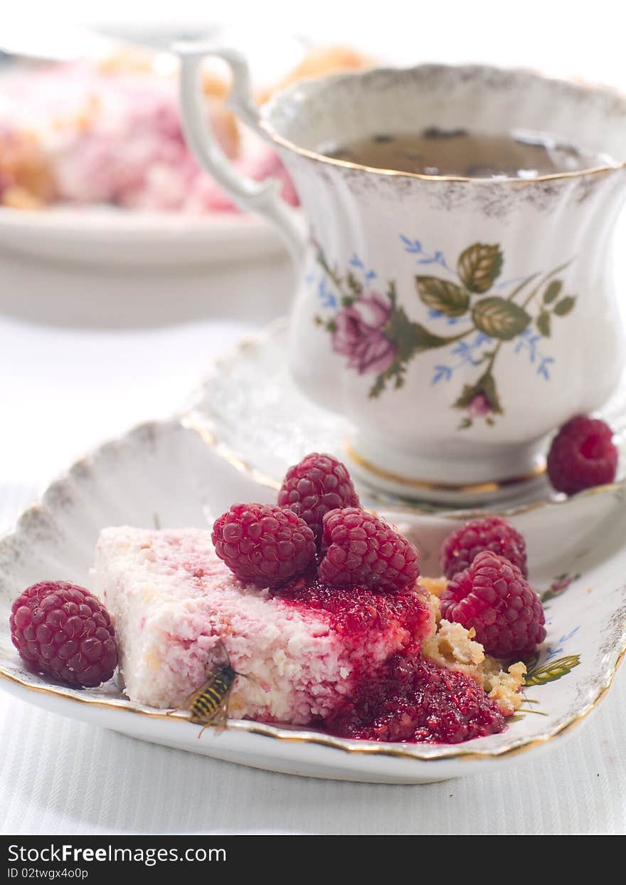 Cheesecake  with raspberry on plate and cup of tea. Cheesecake  with raspberry on plate and cup of tea