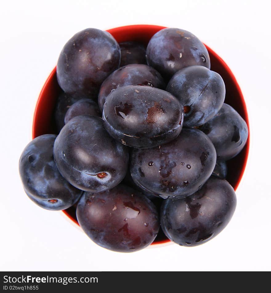 Plums in a bowl on white background