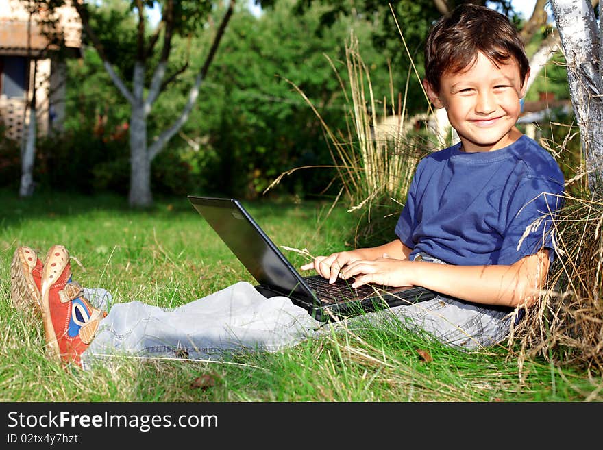 Boy with notebook sit at tree outdoors