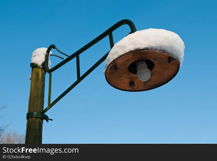 A retro street lantern with snow on it