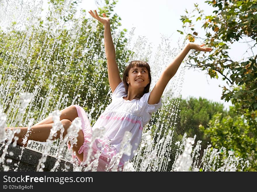 Beautiful woman sitting among the streams of the fountain. Beautiful woman sitting among the streams of the fountain