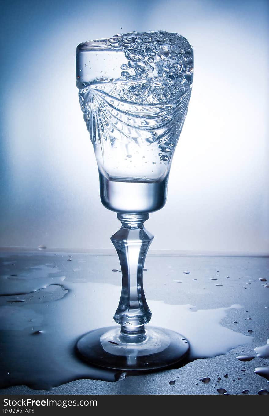 Water splash in glass on blue background