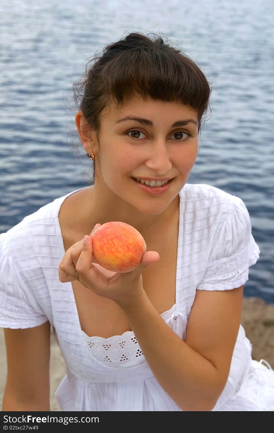 Young girl with the peach near the sea