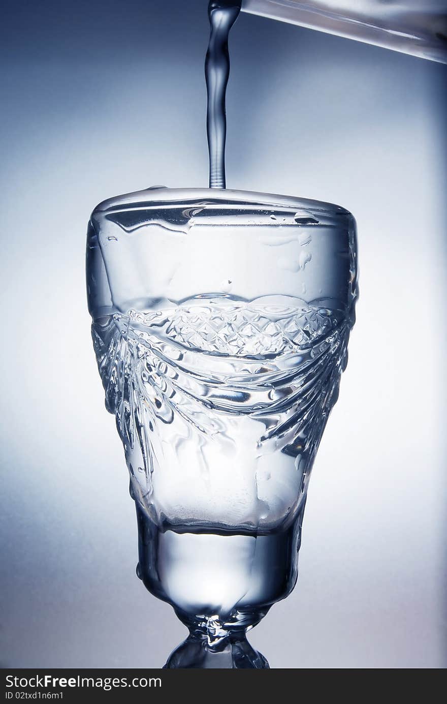 Flowing water in a glass in blue colors