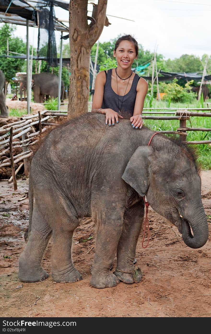 Teenager with baby elephant, delightful young animal of three month