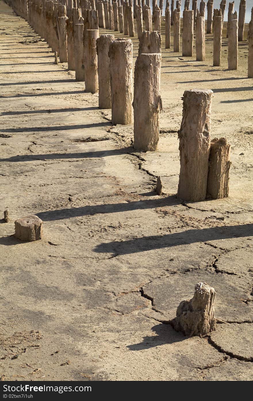 The old wooden destroyed columns on the dried up earth