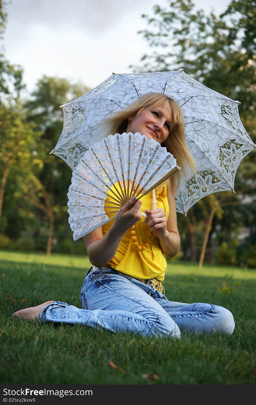 A young woman holds a parasol and a fan. A young woman holds a parasol and a fan.