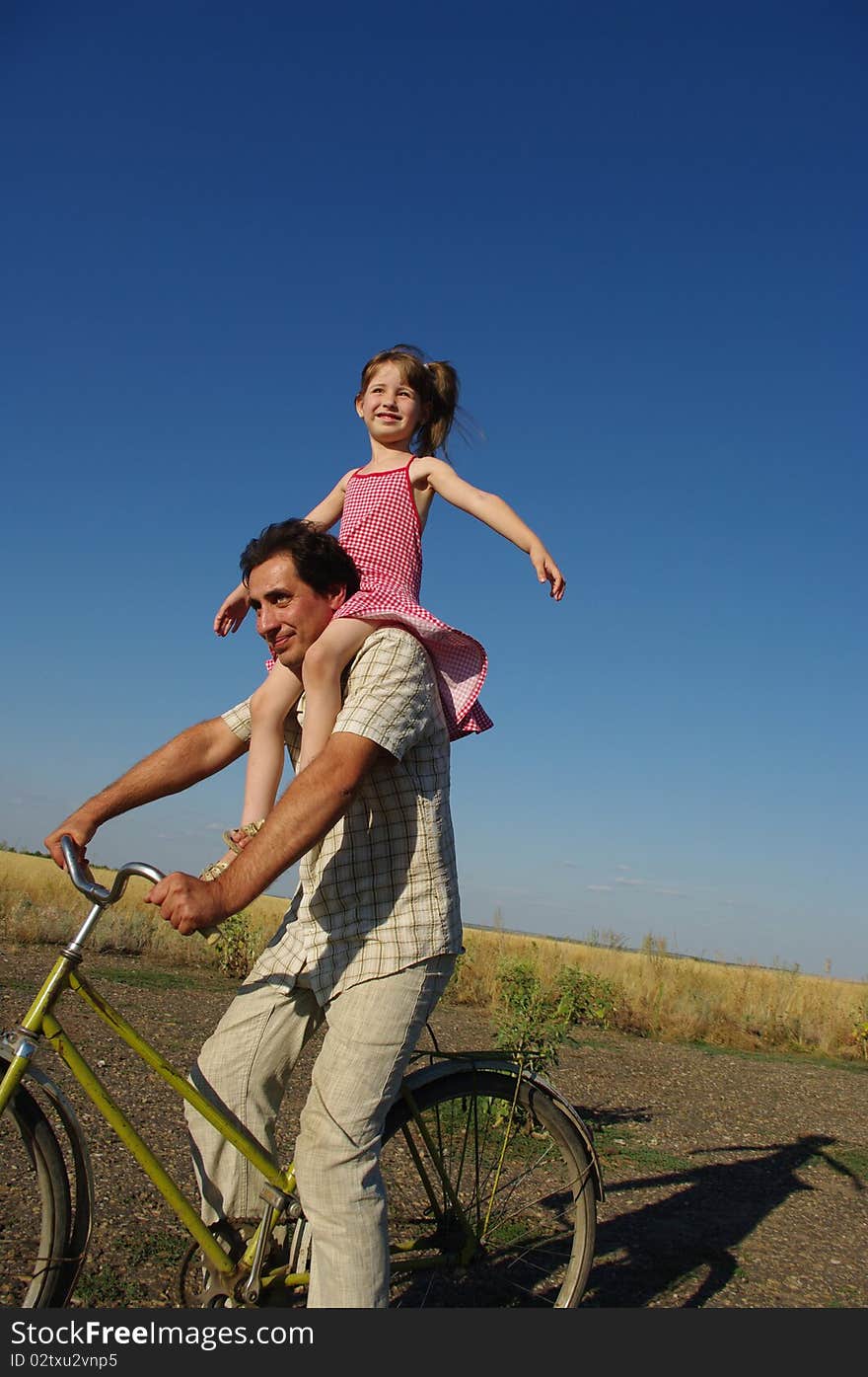 The father rolls a daughter on a bicycle. The father rolls a daughter on a bicycle