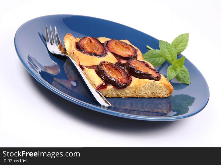 Piece of Plum Pie on a blue plate decorated with a mint twig