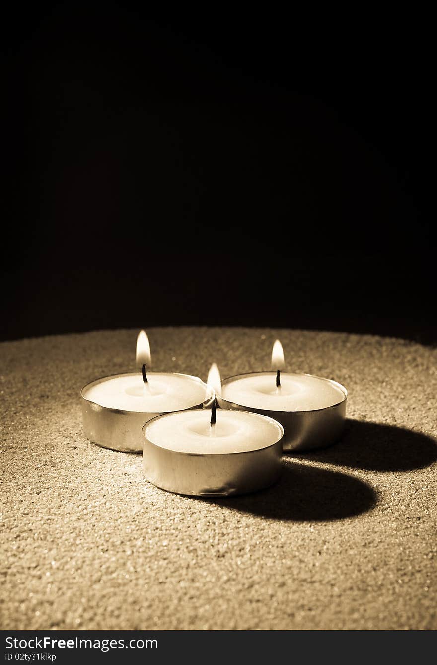 Three Lit Candles on Sand in Single Point Abstract Lighting. Three Lit Candles on Sand in Single Point Abstract Lighting