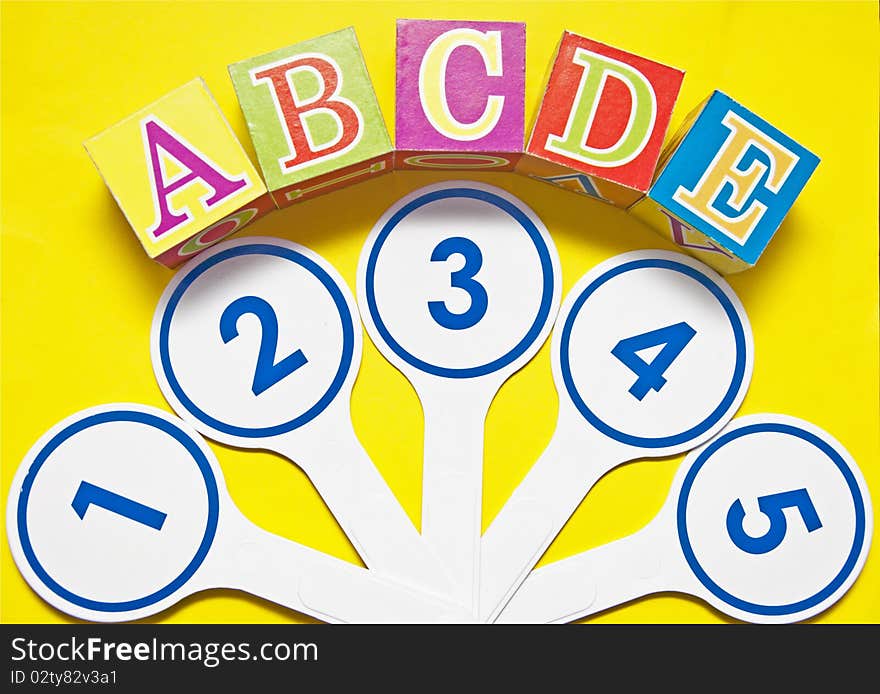 Plastic numbers and alphabetblocks on yellow background