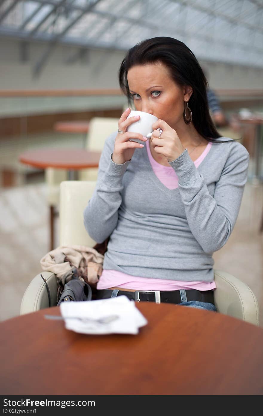 Beautiful young girl is drinking coffee in the shopping mall. Beautiful young girl is drinking coffee in the shopping mall