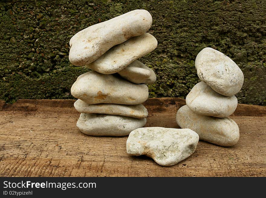 Balancing Stones on a wooden board against the old plaster