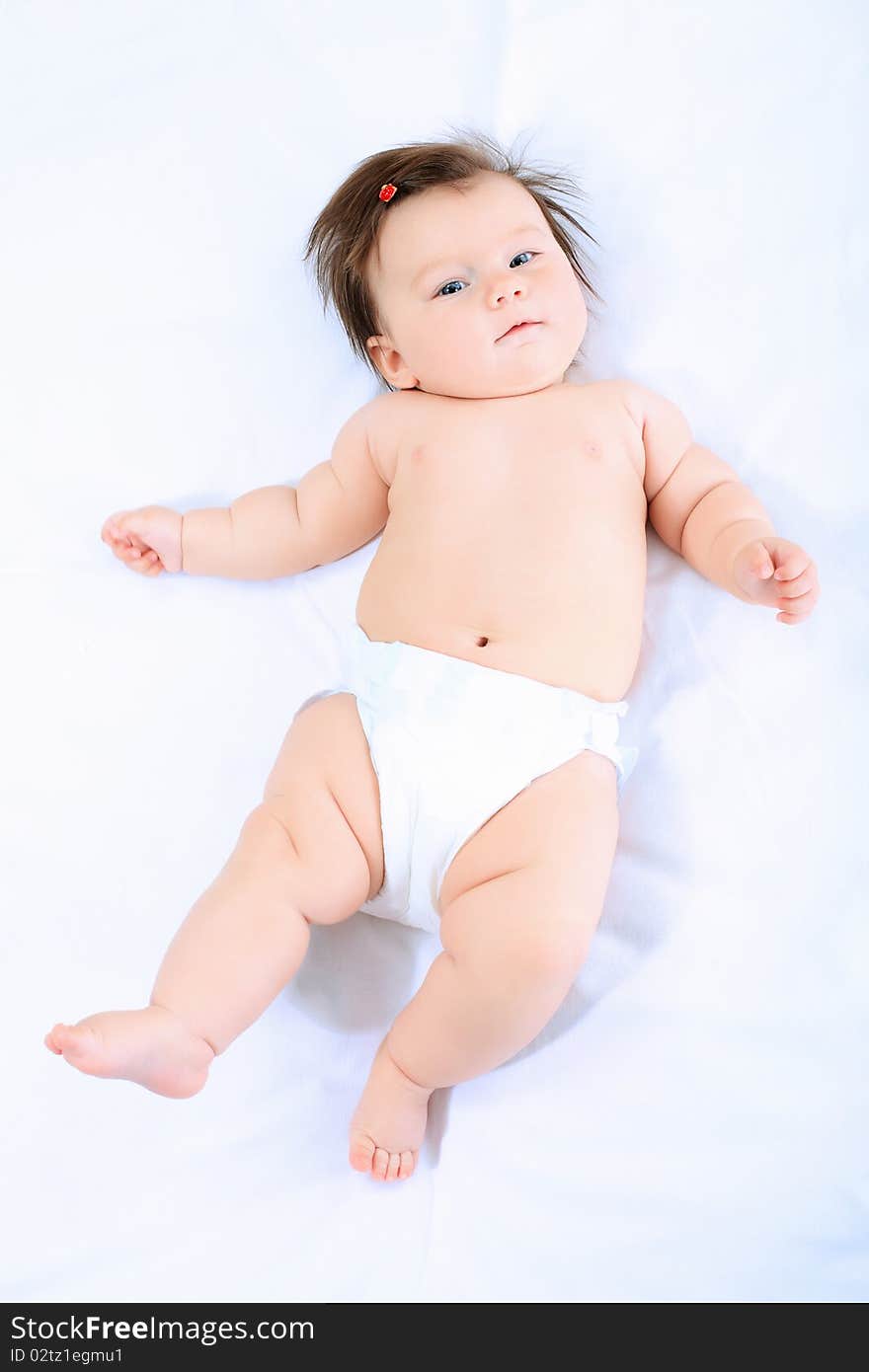 Portrait of a beautiful baby in nappy lying on a white towel. Portrait of a beautiful baby in nappy lying on a white towel.