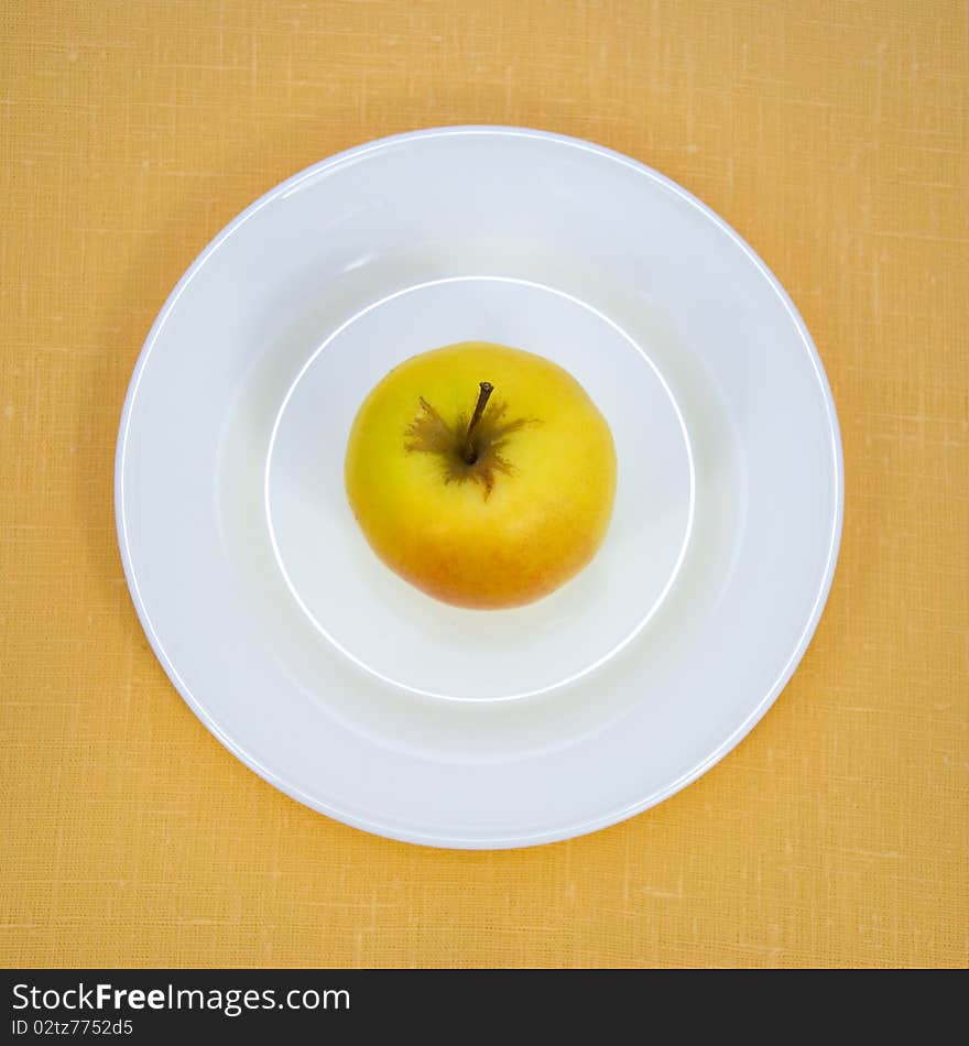 Apple on white plate over linen background.