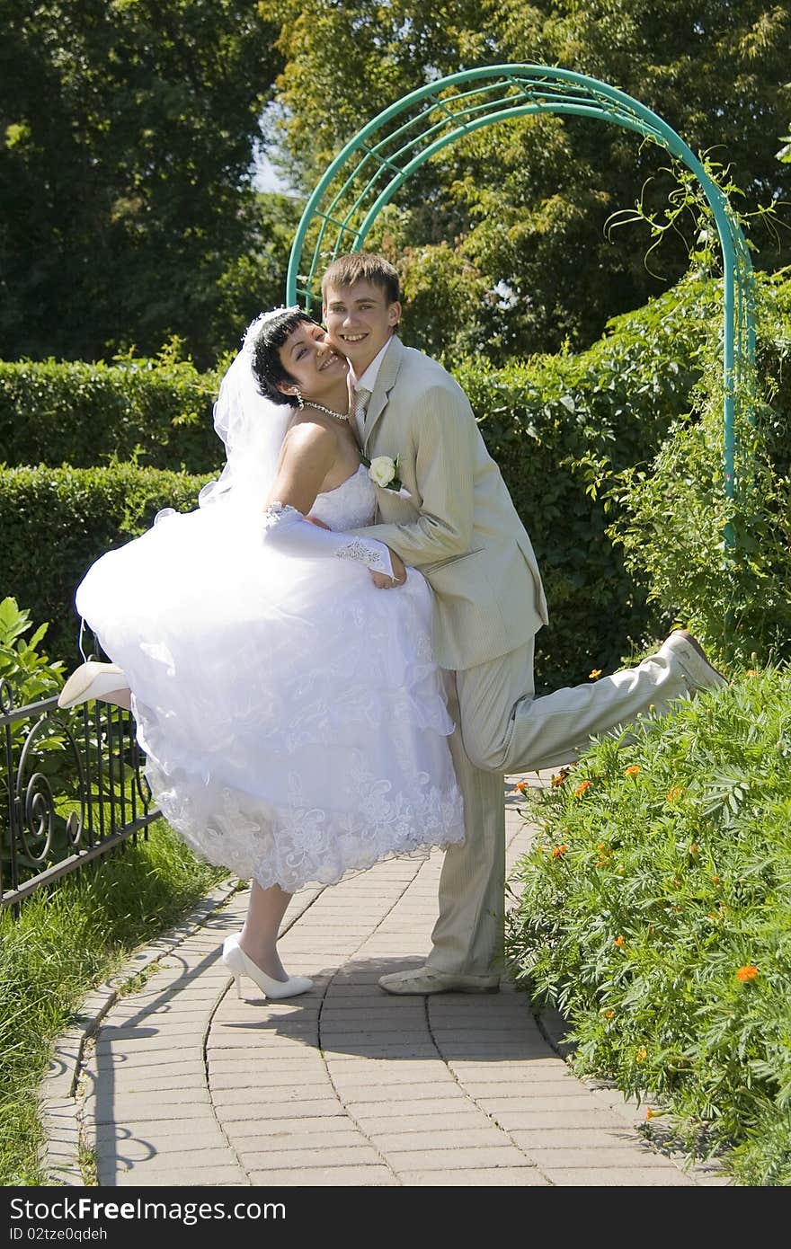 Happy groom and the bride kiss in park. Happy groom and the bride kiss in park