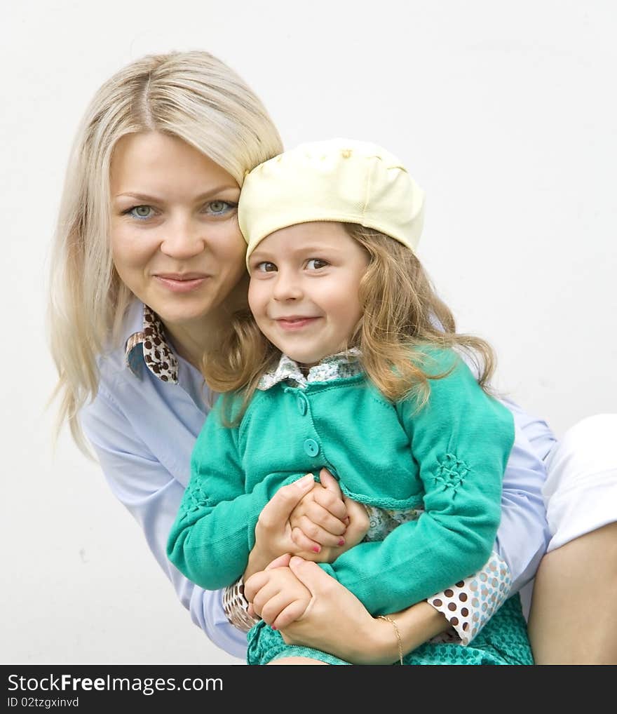 Happy mum and daughter embrace on the white. Happy mum and daughter embrace on the white