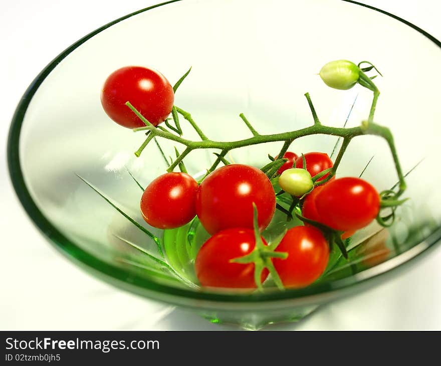 Cluster of cherry tomatoes in a small transparent plate on the white isolated background. Cluster of cherry tomatoes in a small transparent plate on the white isolated background