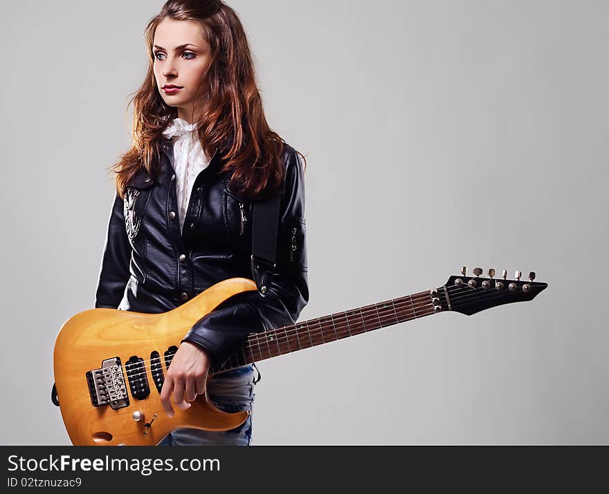 Portrait of a beautiful stylish woman with electric guitar on gray background