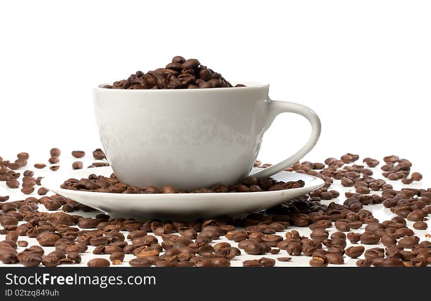 White espresso cup full of beans sat on coffee beans