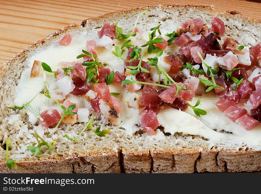 A bread with butter, cress and cracklings on a wooden table. A bread with butter, cress and cracklings on a wooden table