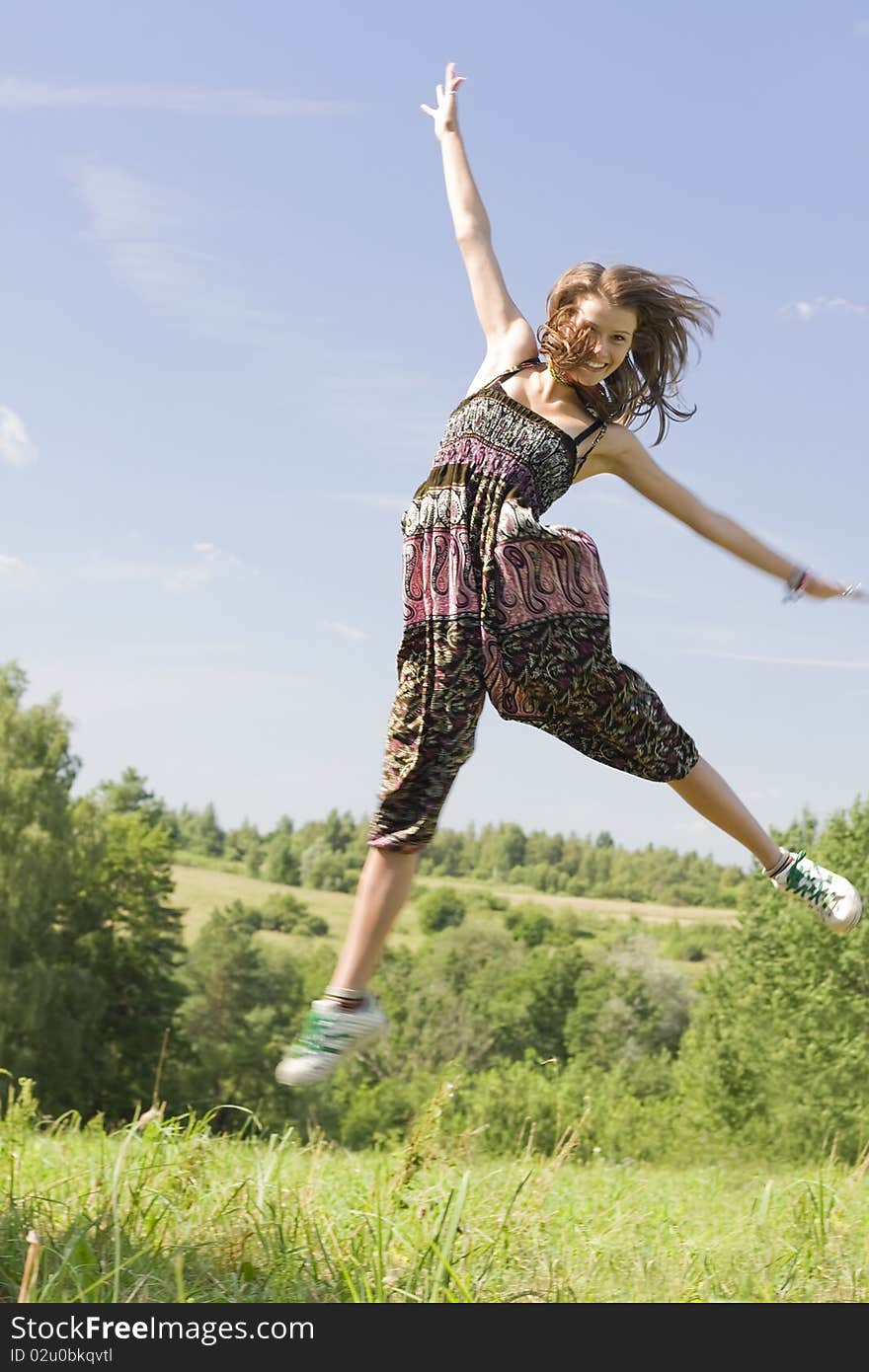 Young happy woman jumping on a green meadow