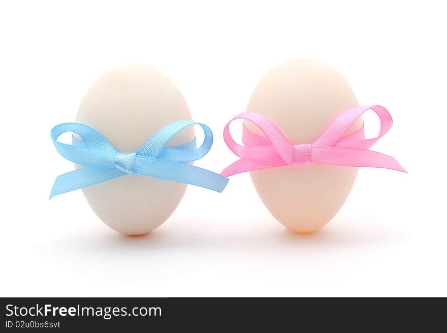 White eggs with ribbons over white background