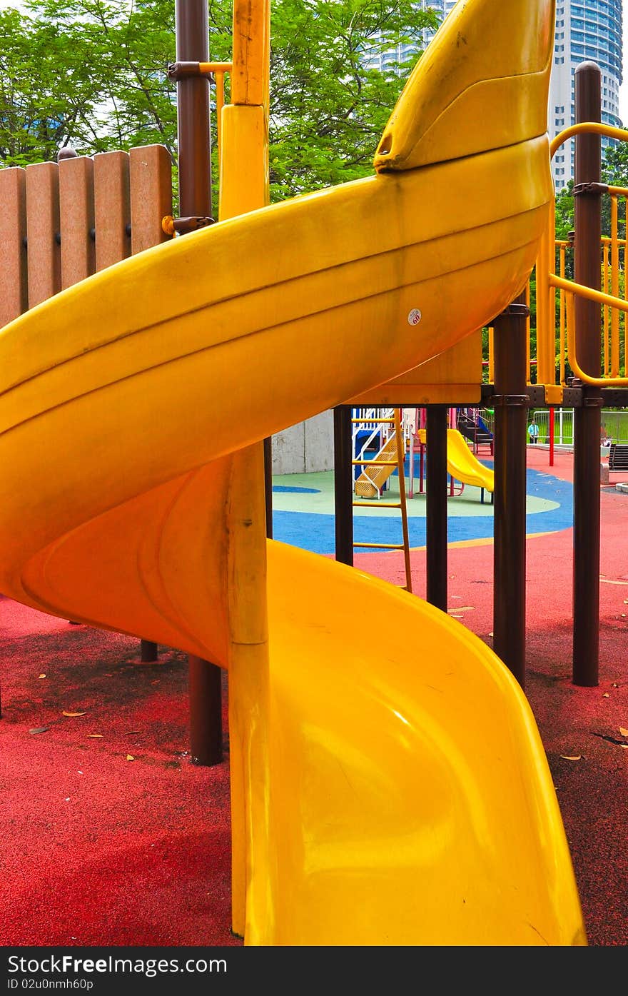 A yellow twisted kiddie slide on the playground. A yellow twisted kiddie slide on the playground