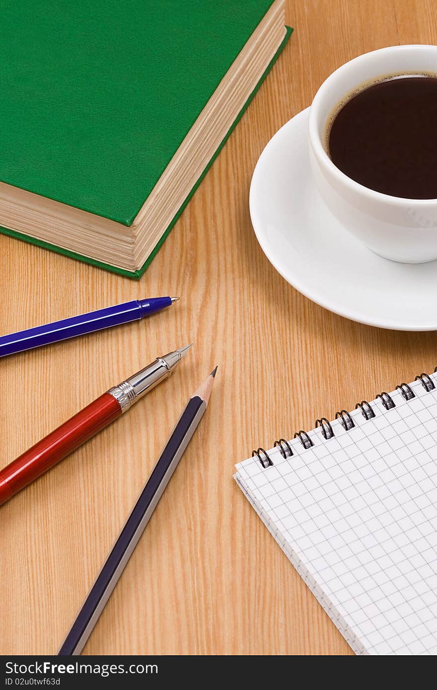 Green book and cup of coffee on table